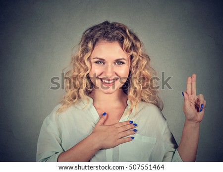 Young happy woman in glasses making a promise isolated on gray wall background
