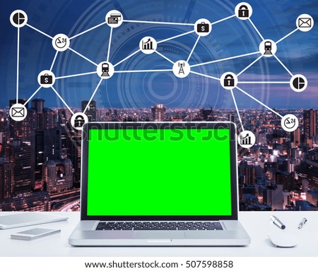 Blank green screen laptop computer with night cityscape and digital technology diagram concept