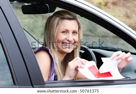 Jolly young female driver tearing up her L sign sitting in her car