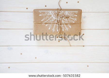 White snowflakes painted on gifts of kraft paper. Background of white wood.