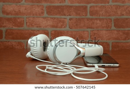 headphones with cellphone on wooden table