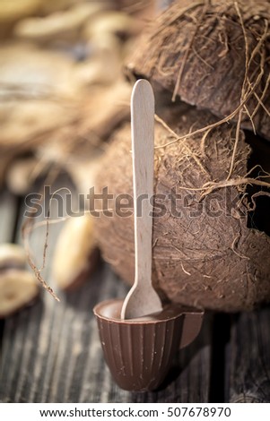 chocolate Lolly in the shape of a small Cup with coconut and nuts on wooden background