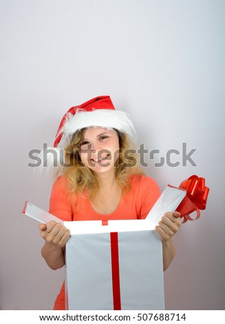Girl in santa hat opening a white gift box with red ribbon