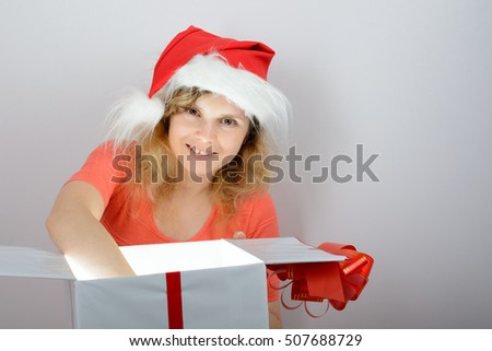 Girl in santa hat opening a white gift box with red ribbon