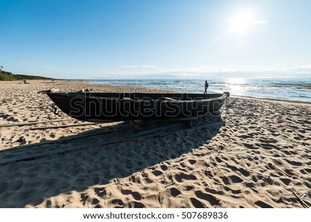 comfortable beach of the baltic sea with rocks and green vegetation and old boat in summer