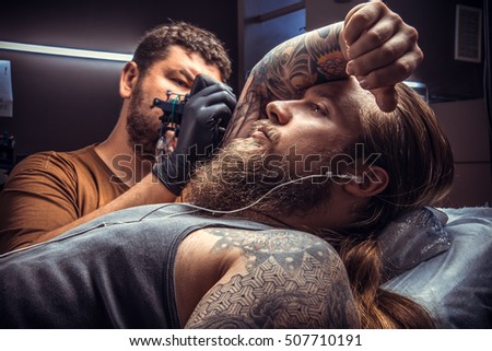 Tattoo specialist makes tattoo pictures in tattoo studio./Professional tattooist making a tattoo in tattoo parlor.