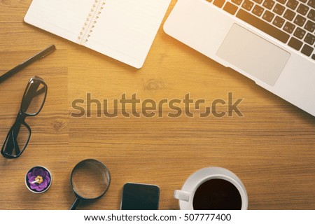 Office table with notepad, laptop, smart phone and coffee cup.View from above with copy space.Hot black coffee cup on wooden background.Spy work place concept.Concept ideas.