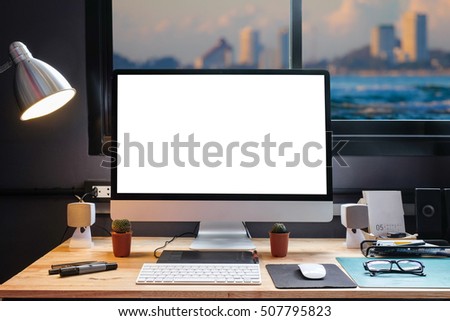 Graphic designer's workspace equipped with a pen tablet, a computer and white screen for text with beautiful sunset on the beach from the window