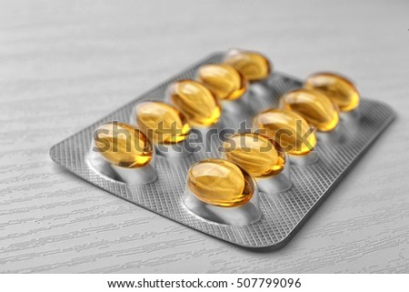 Blister package of cod liver oil capsules on white wooden background