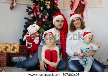 big happy family sitting in Santas caps near the Christmas tree