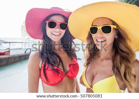 Happy smiling female friends in bikini and sunhats on vacation