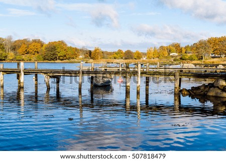 Typical coastline in southern Sweden in fall. Wooden piers and calm water with colorful nature in background. Royalty-Free Stock Photo #507818479