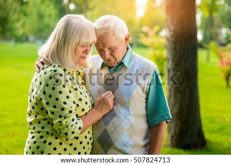 Sad senior couple outdoor. Man and woman looking down. I'm always with you. Go through troubles together.