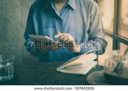 Adult man using small tablet pc while breaking from writing something in cafe on weekend afternoon. Weekend lifestyle with technology concept with vintage filter effect