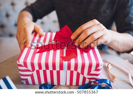 Man decorating gift box with red bow. Christmas gifts handmade wrapping. Surprise, love, friendship, surprise concept