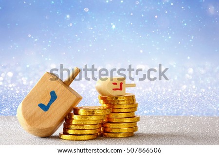 Image of jewish holiday Hanukkah with wooden dreidel (spinning top) and chocolate coins on the glitter background