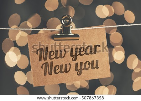 New year new you sign pegged to a string with blurred bokeh lights in the background