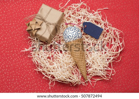 Christmas baubles and decorations including gift with thread, golden bow, white blue christmas ball, ice cream cone, blue tag on red texture background