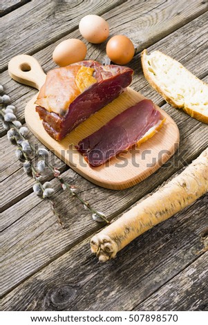 pork, eggs, slice of bread and horse radish with catkin twigs on old wood table 