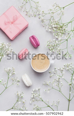 Morning cup of coffee, cake macaron, gift or present box and flower on gray table from above. Beautiful breakfast. Flat lay style.