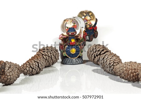 Studio shot of Santa Claus arriving by toy train riding through dry pine cones on white background