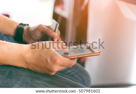 Selective focus young man using old phone with credit card for business investment