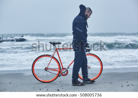 man walking with an orange bike in the winter