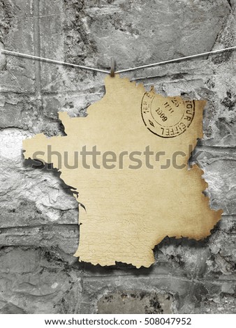 Close-up of one hanged vintage France shape old postcard with peg against weathered stone wall