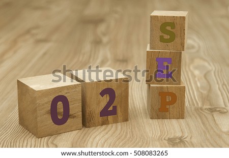 Cube shape calendar for September 02 on wooden surface.