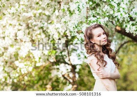 Beautiful woman posing near apple-tree in blossom