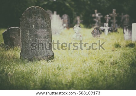 Tombstone and graves in an ancient church graveyard Royalty-Free Stock Photo #508109173