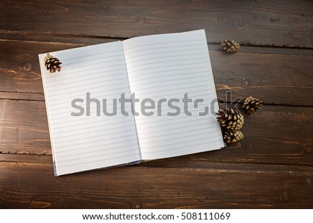 top image of open notebook with blank pages, next to pine cones 