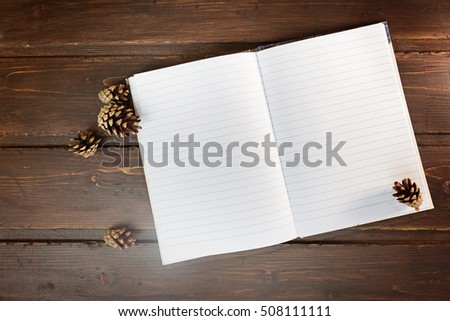 top image of open notebook with blank pages, next to pine cones 