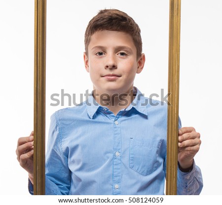 Emotional boy brunette in a blue shirt with a picture frame in the hands on a white background