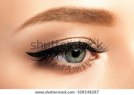 Close up view of gray woman eye with beautiful golden shades and black eyeliner makeup. Classic make up. Studio shot Royalty-Free Stock Photo #508148287