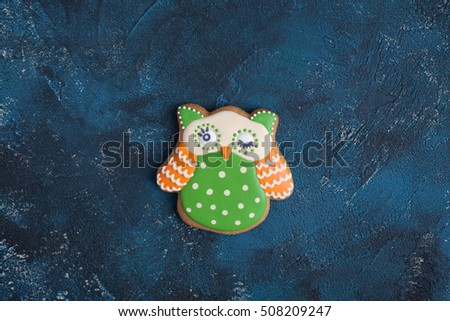 Homemade gingerbread cookie in the form of an orange green owl on the wooden table. Space for text and selective focus.