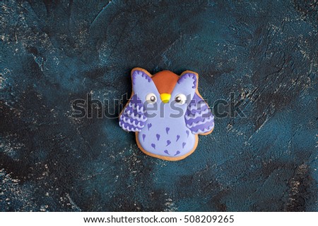 Homemade gingerbread cookie in the form of an purple owl on the wooden table. Space for text and selective focus.
