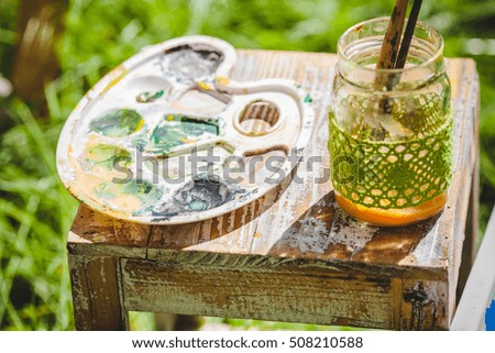 Palette, brushes and canvas in the garden on the table