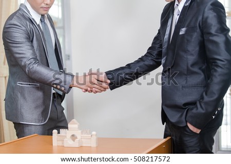 Architecture, home renovation and construction concept - builder with model of building shaking partner hand. Business man handshake.