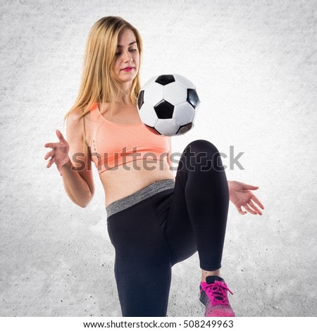 Pretty blonde girl holding a soccer ball on textured background