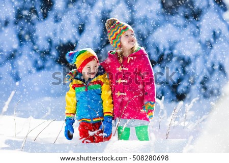 Children play in snowy forest. Toddler kids outdoors in winter. Friends playing in snow. Christmas vacation for family with young children. Little girl and boy in colorful jacket and knitted hat.