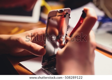 A close-up process of disassemble and dismantle modern mobile phone smartphone with broken shattered display glass and changing details at home