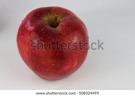Red delicious organic apple on a white background with water droplets