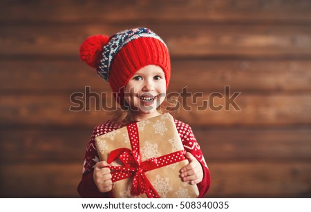 happy child girl with a Christmas present on wooden background
