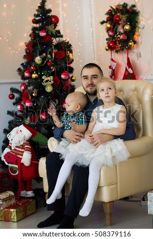 father sitting with children on the couch next to Christmas tree