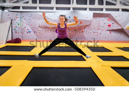 Young sportsman jumping on a trampoline and doing split indoors Royalty-Free Stock Photo #508394350
