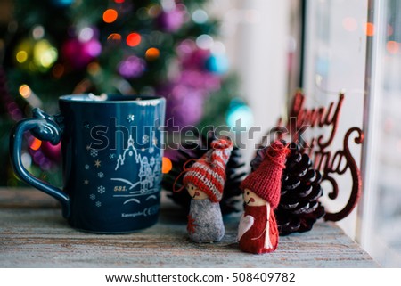 Two knitted dolls and a cup of coffee with christmas background