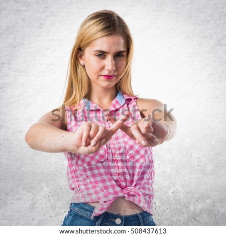 Blonde girl doing NO gesture on textured background