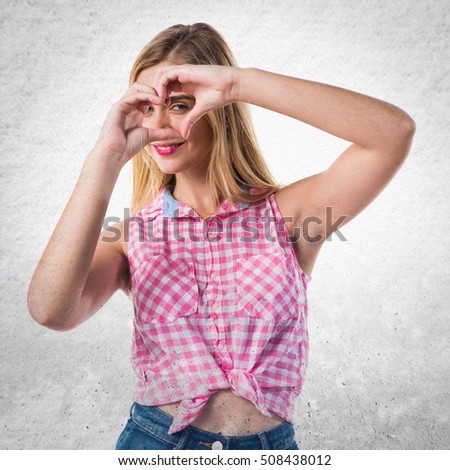 Girl making a heart with her hands on textured background
