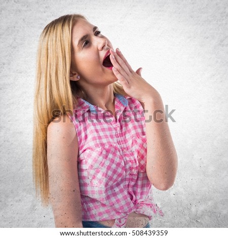 Blonde girl yawning on textured background